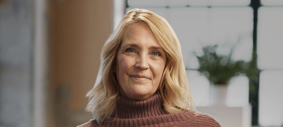 QULIPTA patient Casey wearing a brown sweater