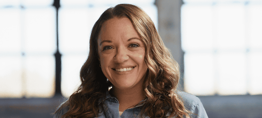 QULIPTA® patient Kelsi wearing a denim jacket and smiling after sharing her migraine preventive treatment story.
