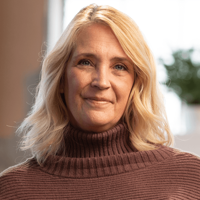 QULIPTA patient Casey wearing a brown sweater